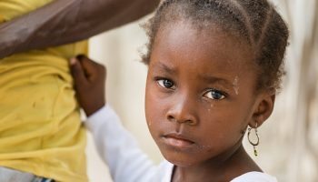 Portrait of African black little girl looking at camera and holding dad's shirt