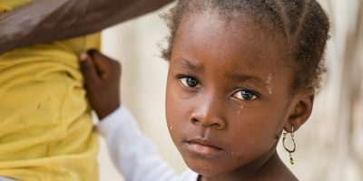 Portrait of African black little girl looking at camera and holding dad's shirt